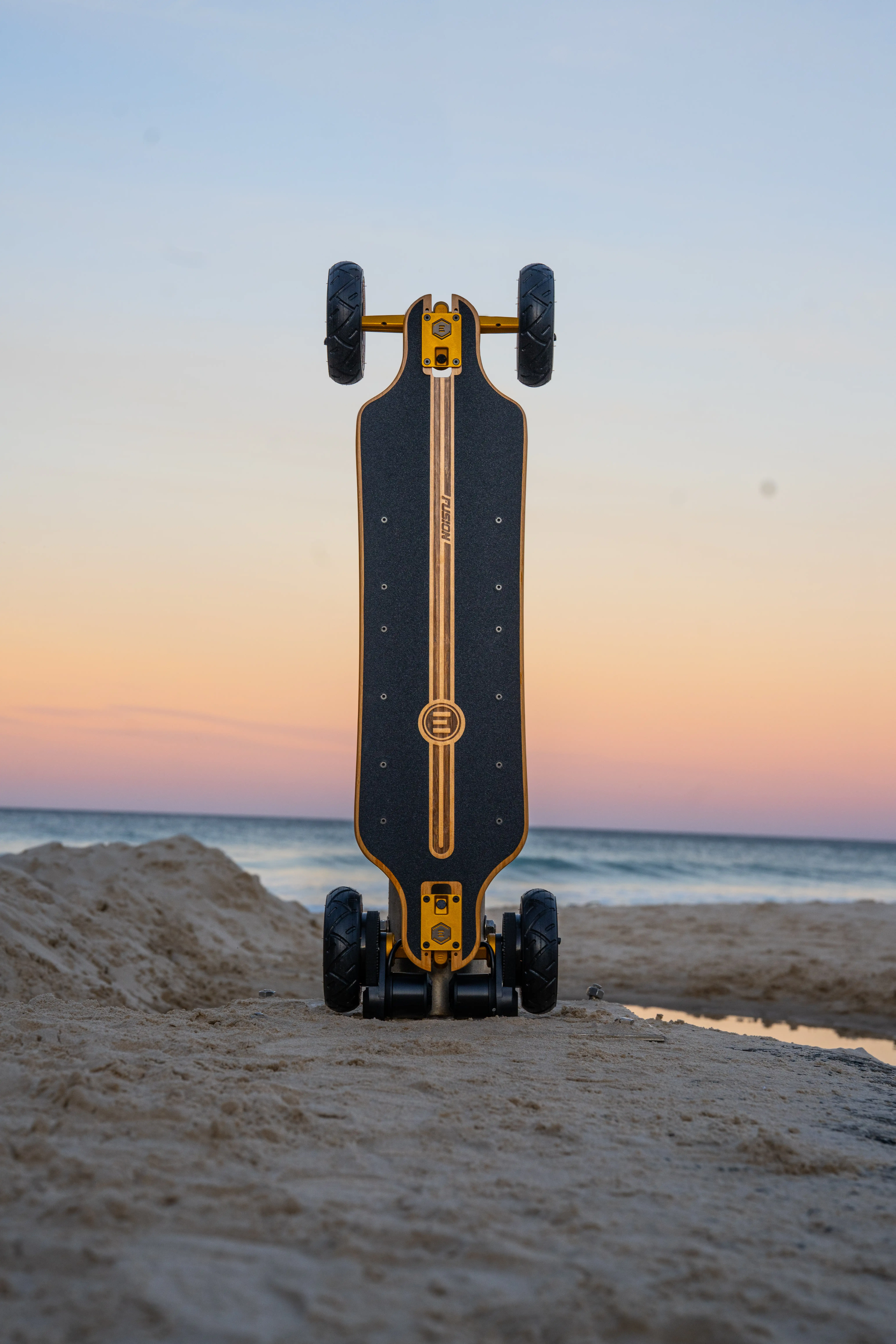 Photo du e-skate Fusion sur une plage à la verticale